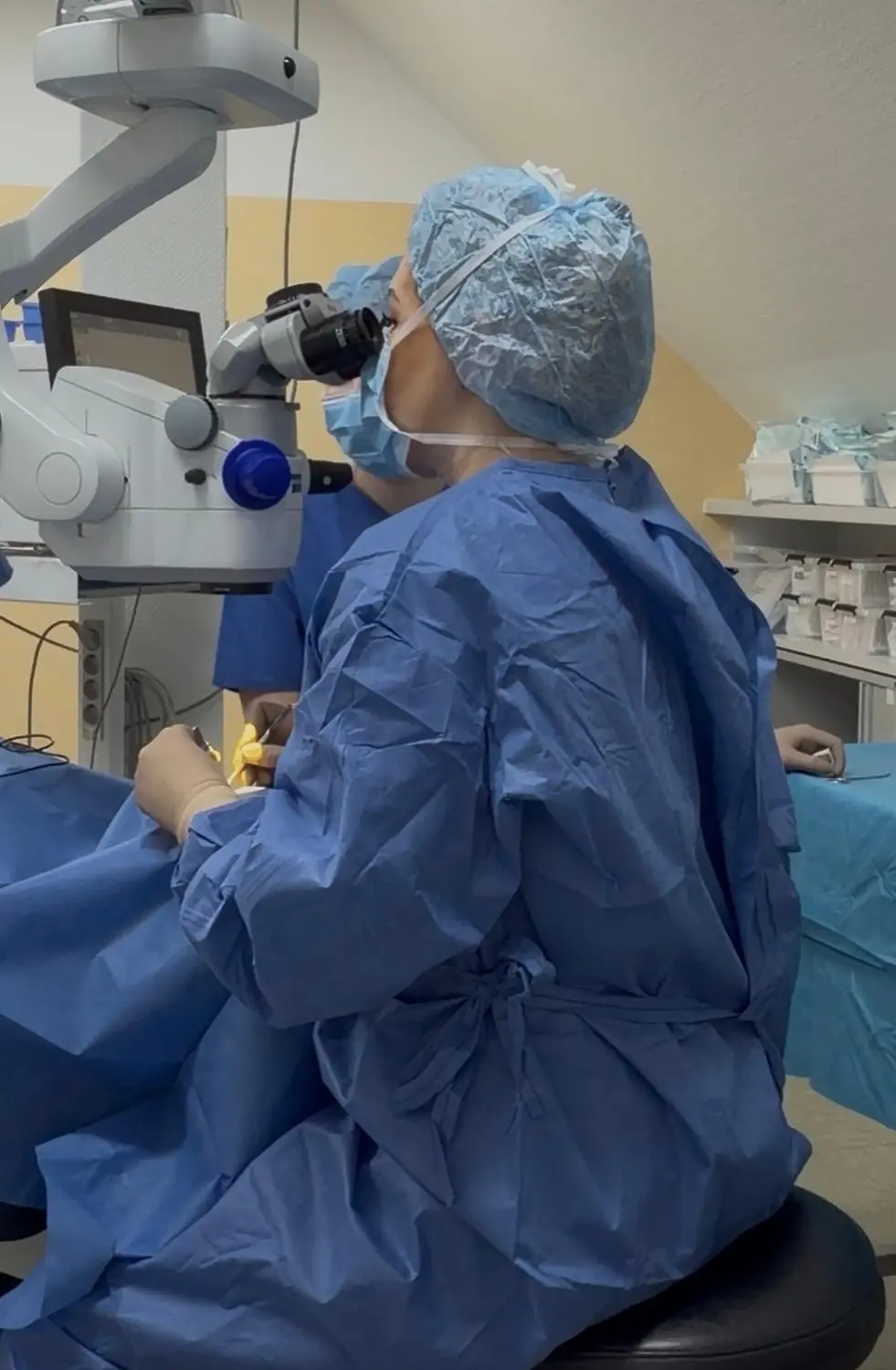 Praxis Olena Behrens – Augenheilkunde – Eine Frau untersucht ein Auge mit einem Ophthalmoskop in einer klinischen Umgebung.